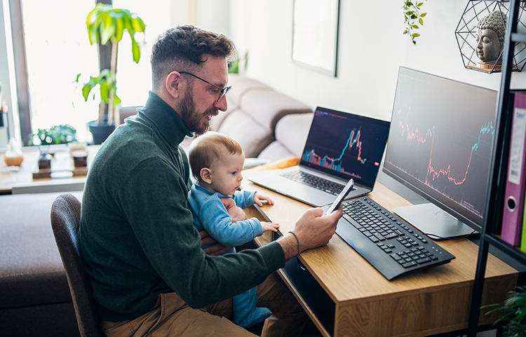 Person sitting at their computer desk with their toddler sitting on their lap